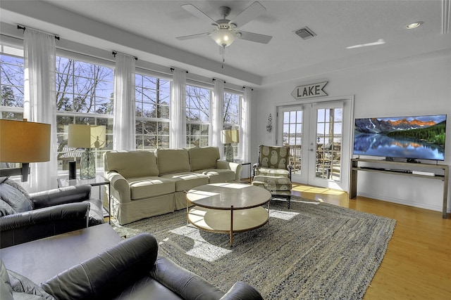 living room featuring light wood finished floors, baseboards, visible vents, a ceiling fan, and french doors