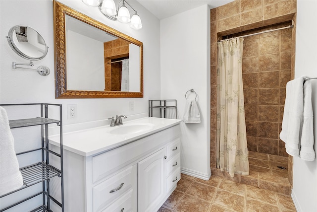 bathroom with a tile shower, vanity, and baseboards