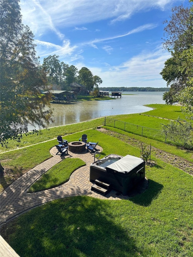 view of yard featuring a patio, an outdoor fire pit, a water view, and fence