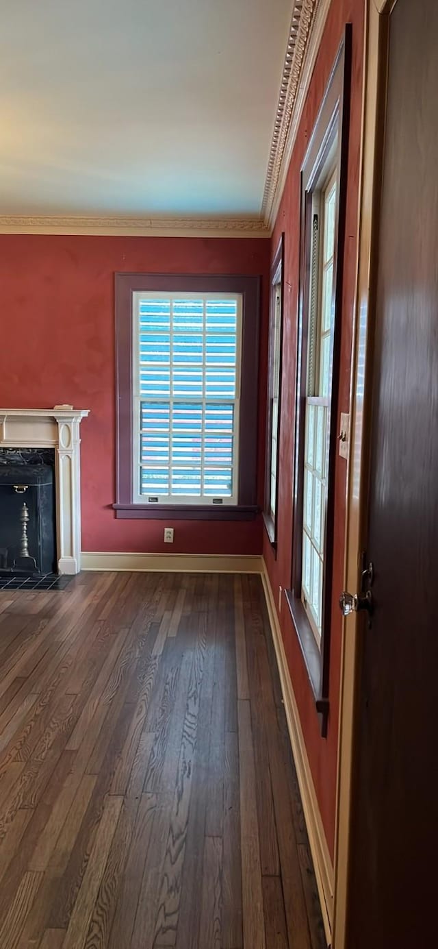 unfurnished living room featuring a premium fireplace, baseboards, dark wood-type flooring, and crown molding