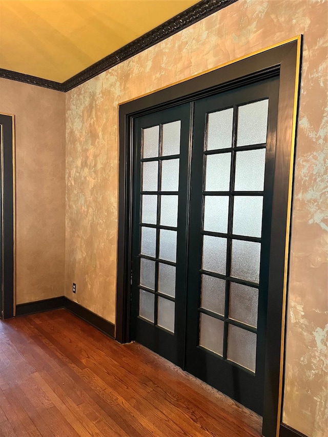 empty room with french doors, wallpapered walls, baseboards, and wood finished floors