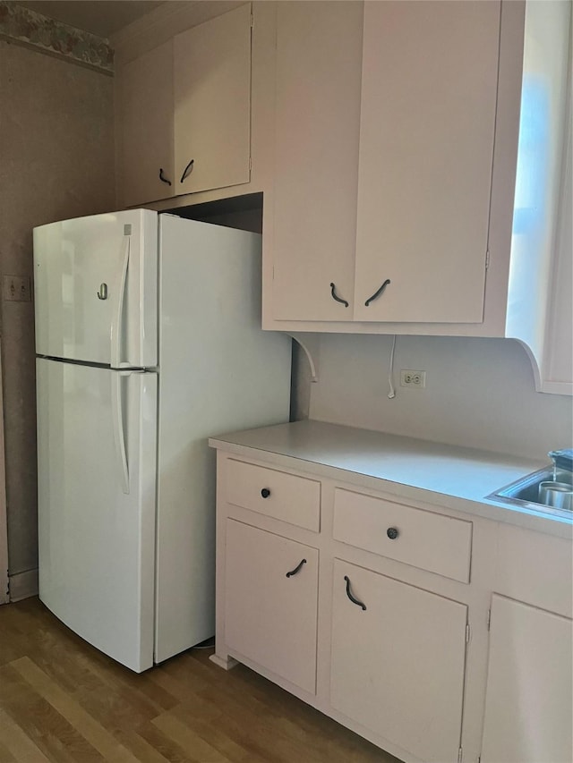 kitchen featuring light countertops, light wood finished floors, freestanding refrigerator, and white cabinets