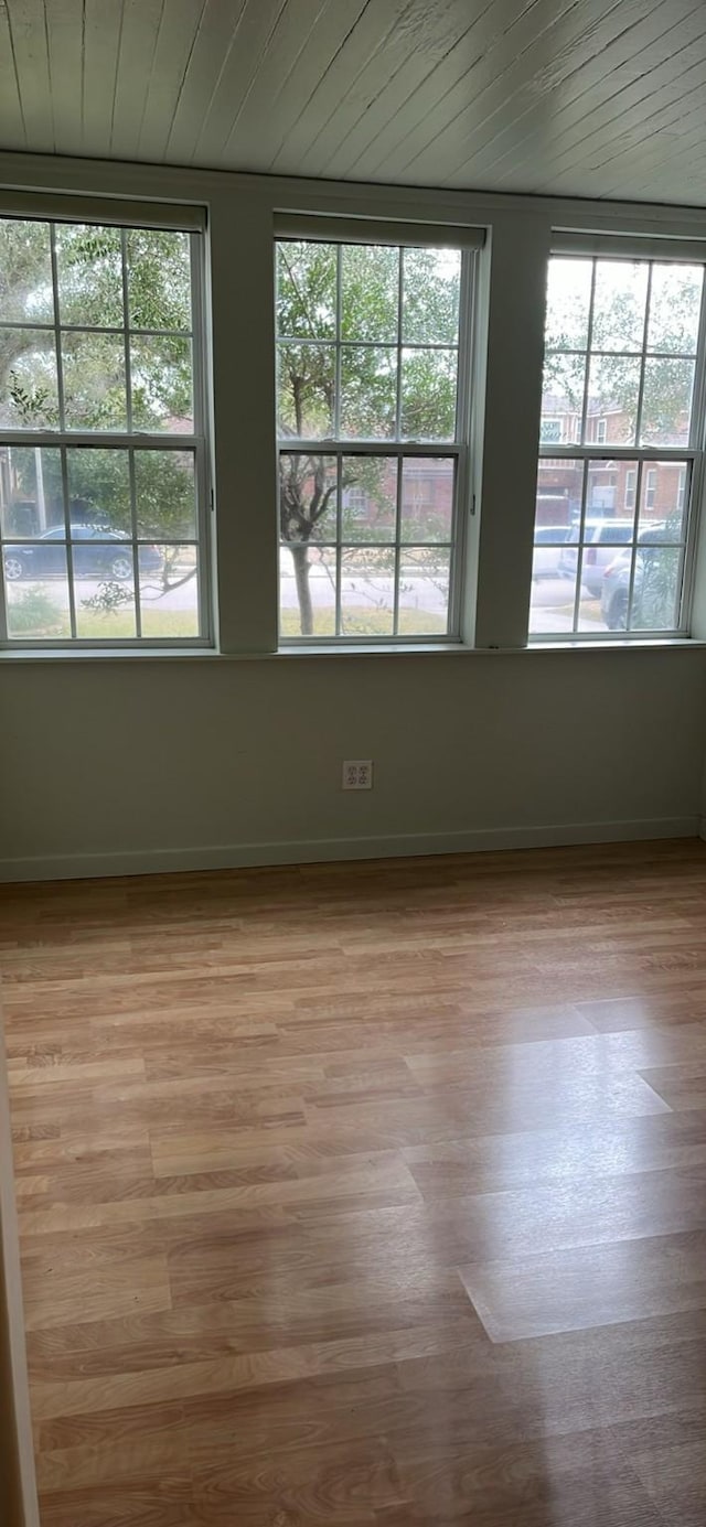 empty room with light wood-style floors, wood ceiling, and baseboards