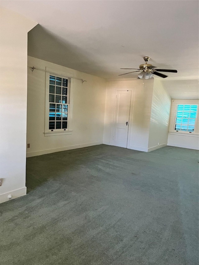 spare room featuring a ceiling fan, dark carpet, and baseboards