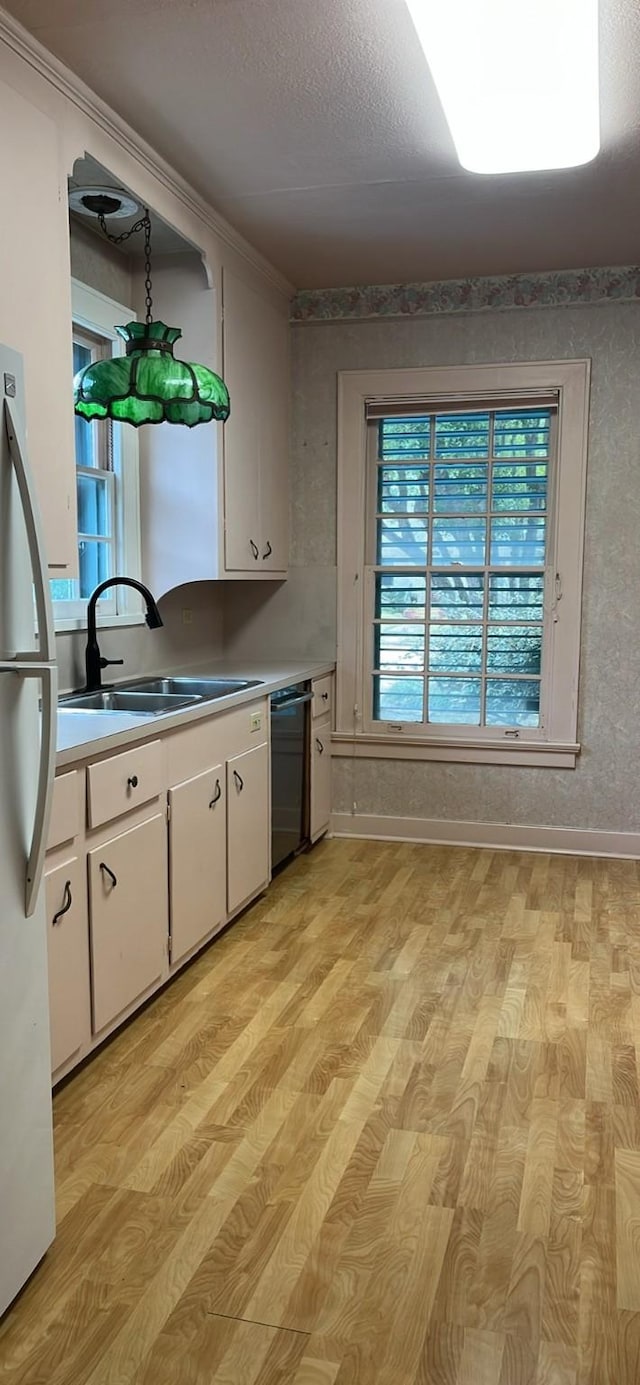 kitchen with a sink, white cabinets, dishwasher, and freestanding refrigerator