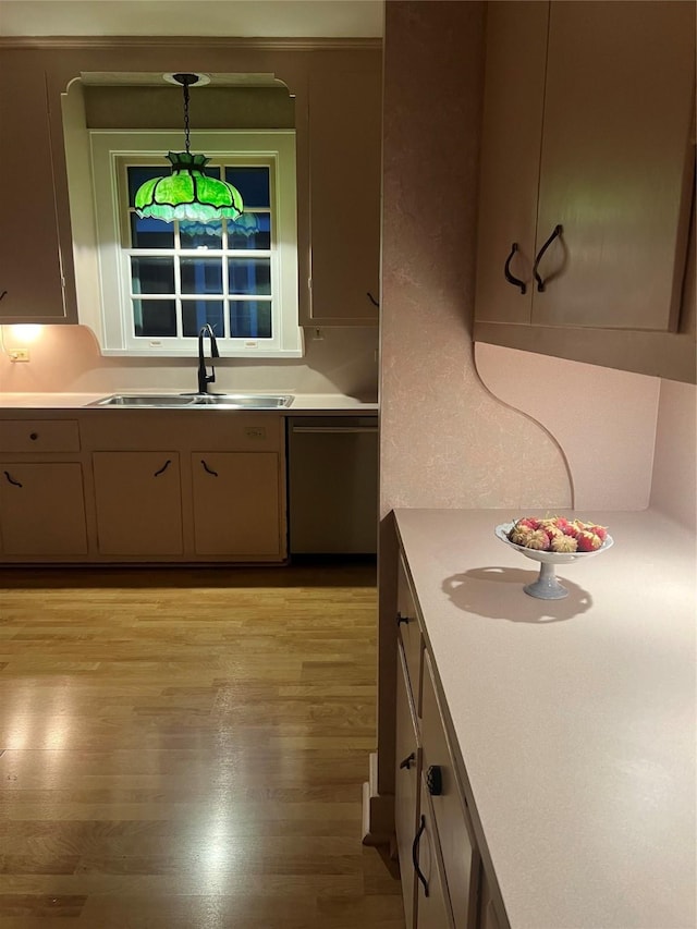 kitchen with hanging light fixtures, light wood-style flooring, light countertops, and a sink