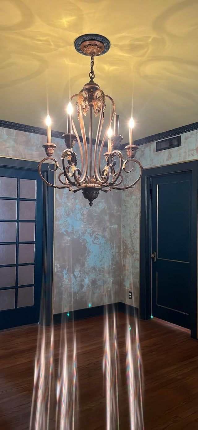 interior space featuring wallpapered walls, dark wood finished floors, and a notable chandelier