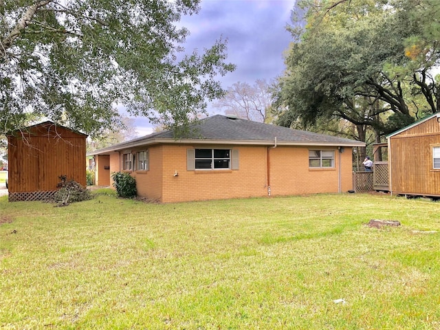 rear view of house featuring a shed and a lawn