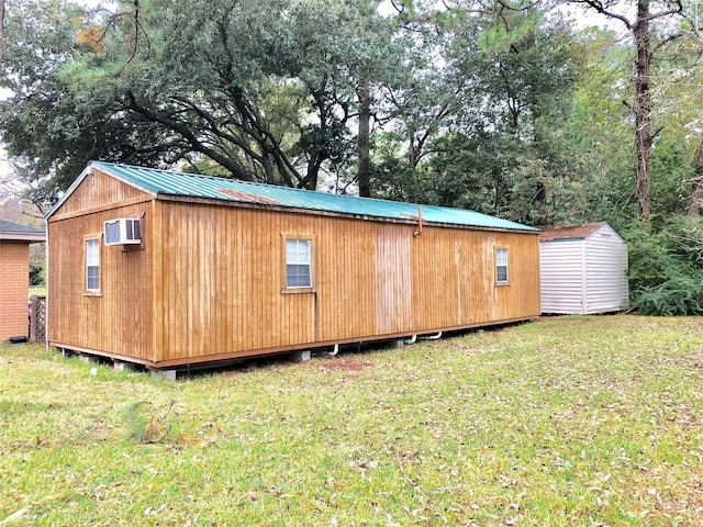 view of outbuilding featuring a wall mounted air conditioner and a yard