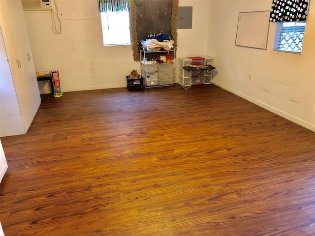 unfurnished room with dark wood-type flooring, a wall mounted air conditioner, and electric panel