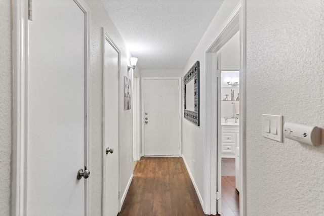 corridor with dark hardwood / wood-style floors and a textured ceiling