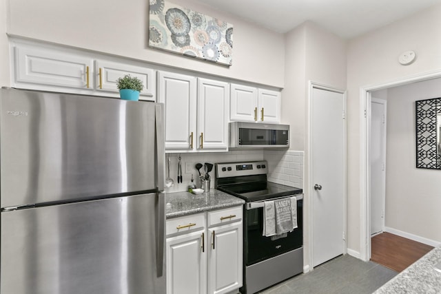 kitchen featuring stainless steel appliances, light stone countertops, white cabinets, and backsplash