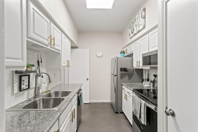 kitchen featuring sink, appliances with stainless steel finishes, backsplash, a skylight, and white cabinets