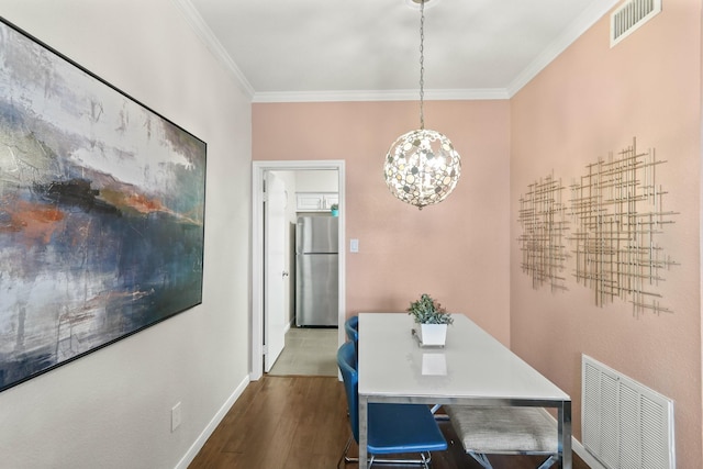 dining area with hardwood / wood-style flooring, ornamental molding, and an inviting chandelier