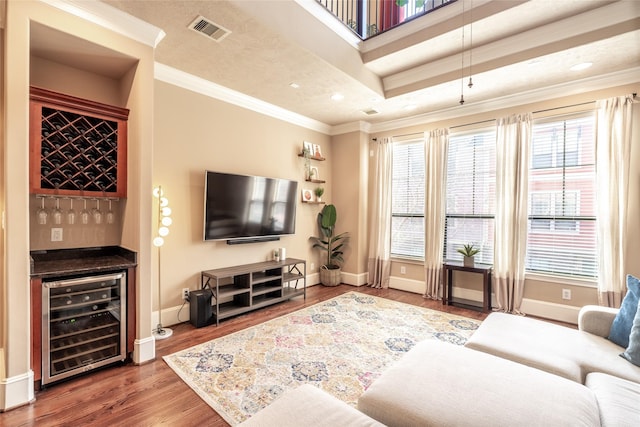 living room with crown molding, indoor bar, a healthy amount of sunlight, and wine cooler