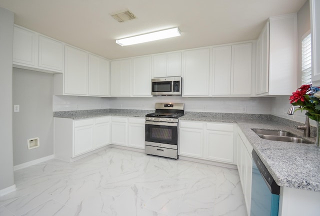 kitchen featuring appliances with stainless steel finishes, sink, white cabinets, and backsplash