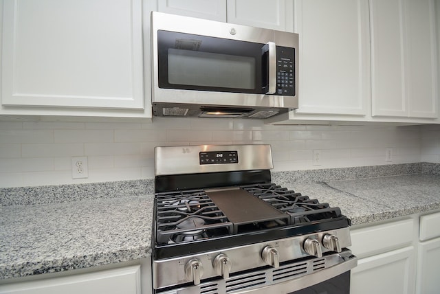 kitchen with white cabinetry, light stone counters, and appliances with stainless steel finishes