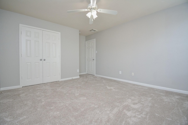 unfurnished bedroom featuring ceiling fan, light carpet, and a closet