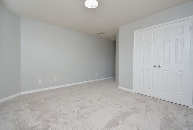 unfurnished bedroom with light colored carpet and a closet