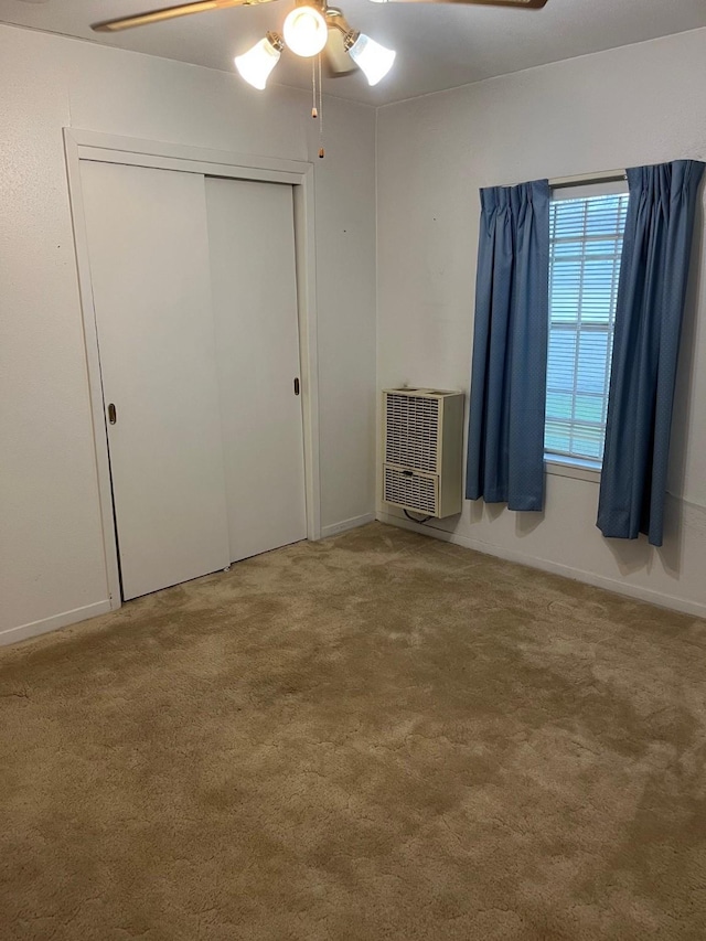 unfurnished bedroom with carpet floors, heating unit, ceiling fan, and a closet