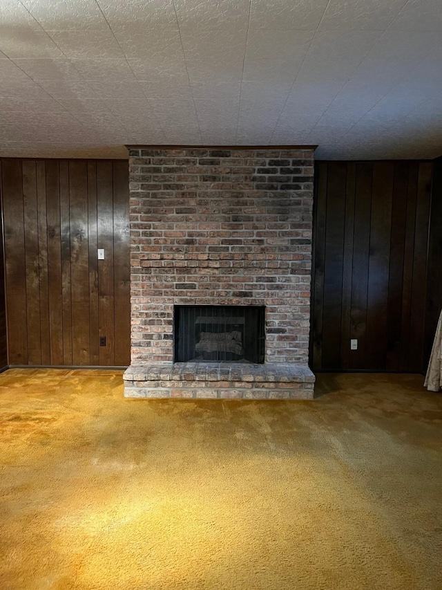 unfurnished living room with wooden walls, carpet floors, and a brick fireplace