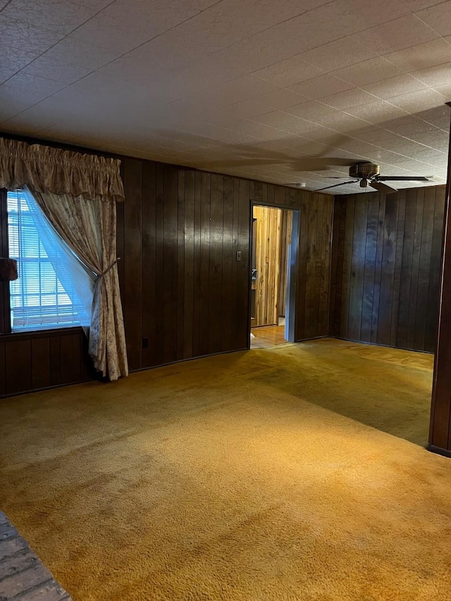 carpeted empty room featuring ceiling fan and wooden walls