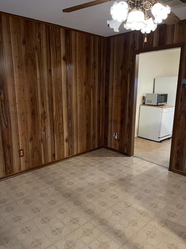 unfurnished room featuring ceiling fan and wood walls