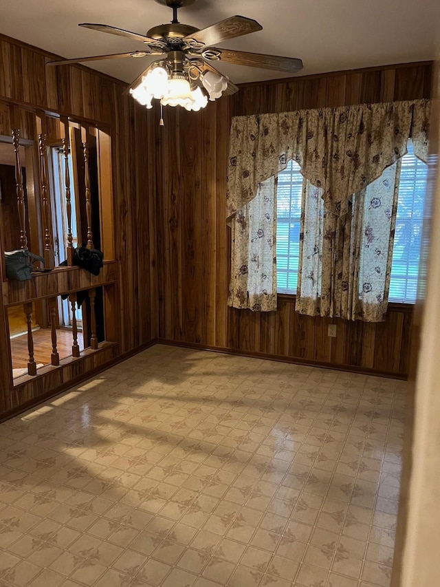 unfurnished room featuring ceiling fan and wood walls