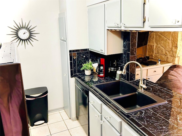 kitchen featuring light tile patterned floors, black dishwasher, tile countertops, white cabinetry, and a sink