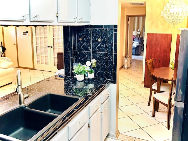 kitchen with tile countertops, light tile patterned floors, a sink, visible vents, and white cabinetry