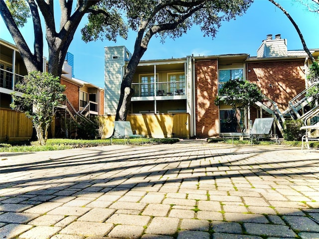 back of property featuring brick siding, a chimney, and a balcony