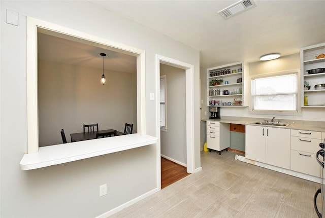 kitchen with hanging light fixtures, white cabinetry, and sink