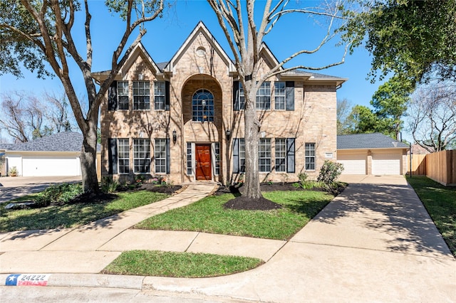 view of front of home featuring brick siding, concrete driveway, an attached garage, fence, and a front lawn