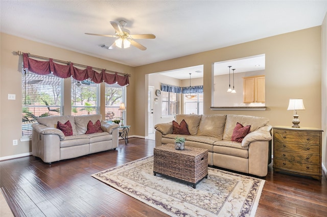 living room featuring dark wood-style floors, a ceiling fan, visible vents, and baseboards