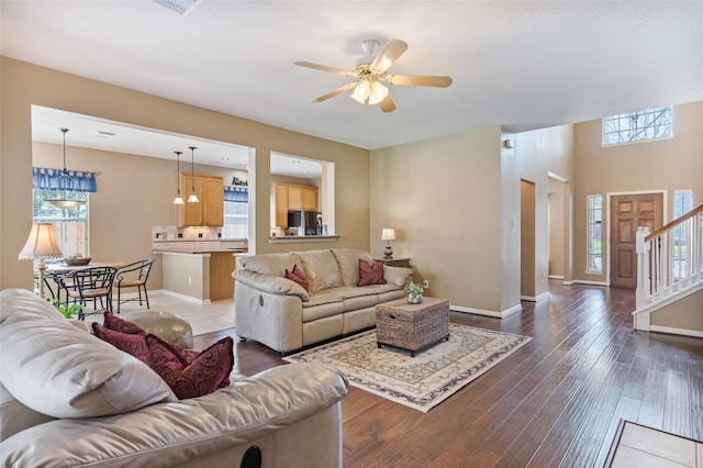 living room with dark wood-style floors, stairway, a ceiling fan, and baseboards