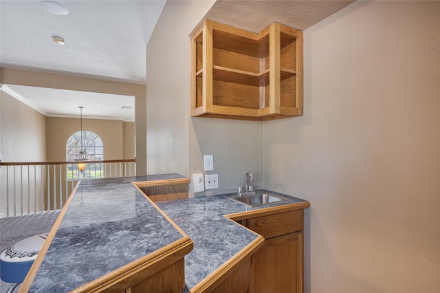 kitchen featuring pendant lighting, crown molding, tile countertops, brown cabinetry, and a sink