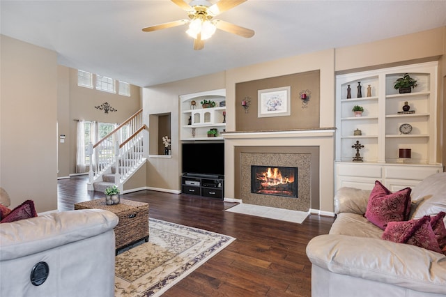 living room with built in shelves, stairway, baseboards, and wood finished floors