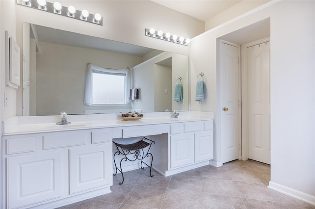 full bath featuring baseboards, double vanity, a sink, and tile patterned floors