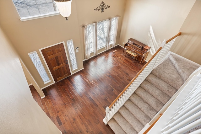 entryway featuring a towering ceiling, baseboards, stairway, and hardwood / wood-style floors