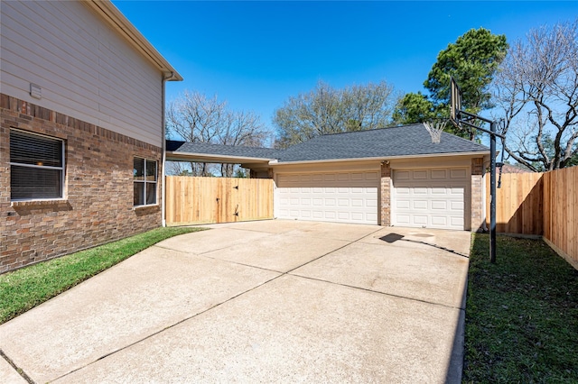 view of side of property with roof with shingles, a detached garage, fence, and a gate