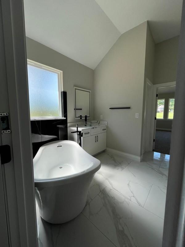 bathroom with vanity, a bathtub, and vaulted ceiling