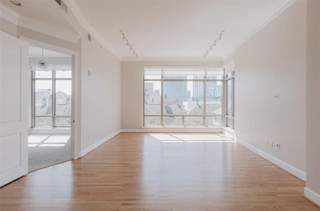 unfurnished room featuring rail lighting, ornamental molding, ceiling fan, and light hardwood / wood-style flooring