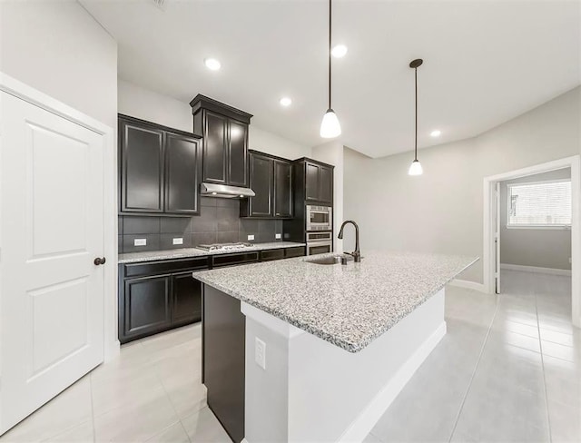 kitchen featuring sink, tasteful backsplash, decorative light fixtures, a center island with sink, and appliances with stainless steel finishes