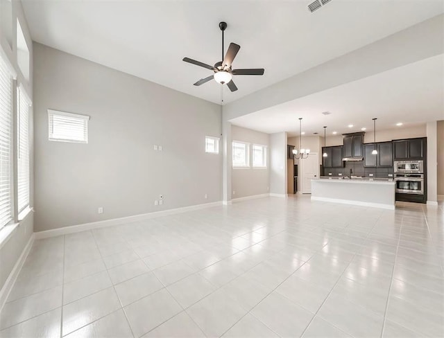 unfurnished living room with ceiling fan with notable chandelier and light tile patterned floors