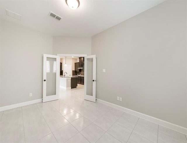 spare room featuring french doors, sink, and light tile patterned floors