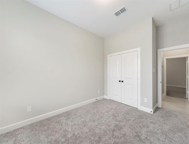 unfurnished bedroom featuring light carpet and a closet