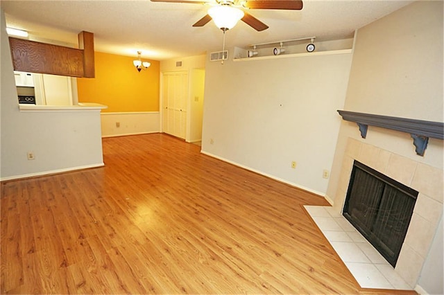 unfurnished living room with a tiled fireplace, light hardwood / wood-style floors, and ceiling fan