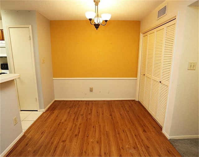 unfurnished dining area with hardwood / wood-style flooring and a chandelier