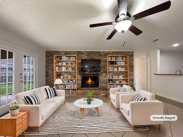 tiled living room with built in shelves, french doors, a textured ceiling, ceiling fan, and a fireplace