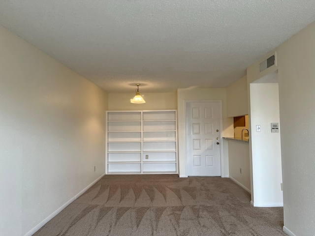 carpeted spare room with a textured ceiling